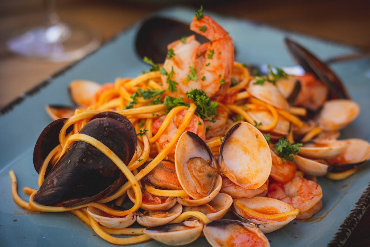 Seafood pasta with mussels, prawns and clams on a blue plate