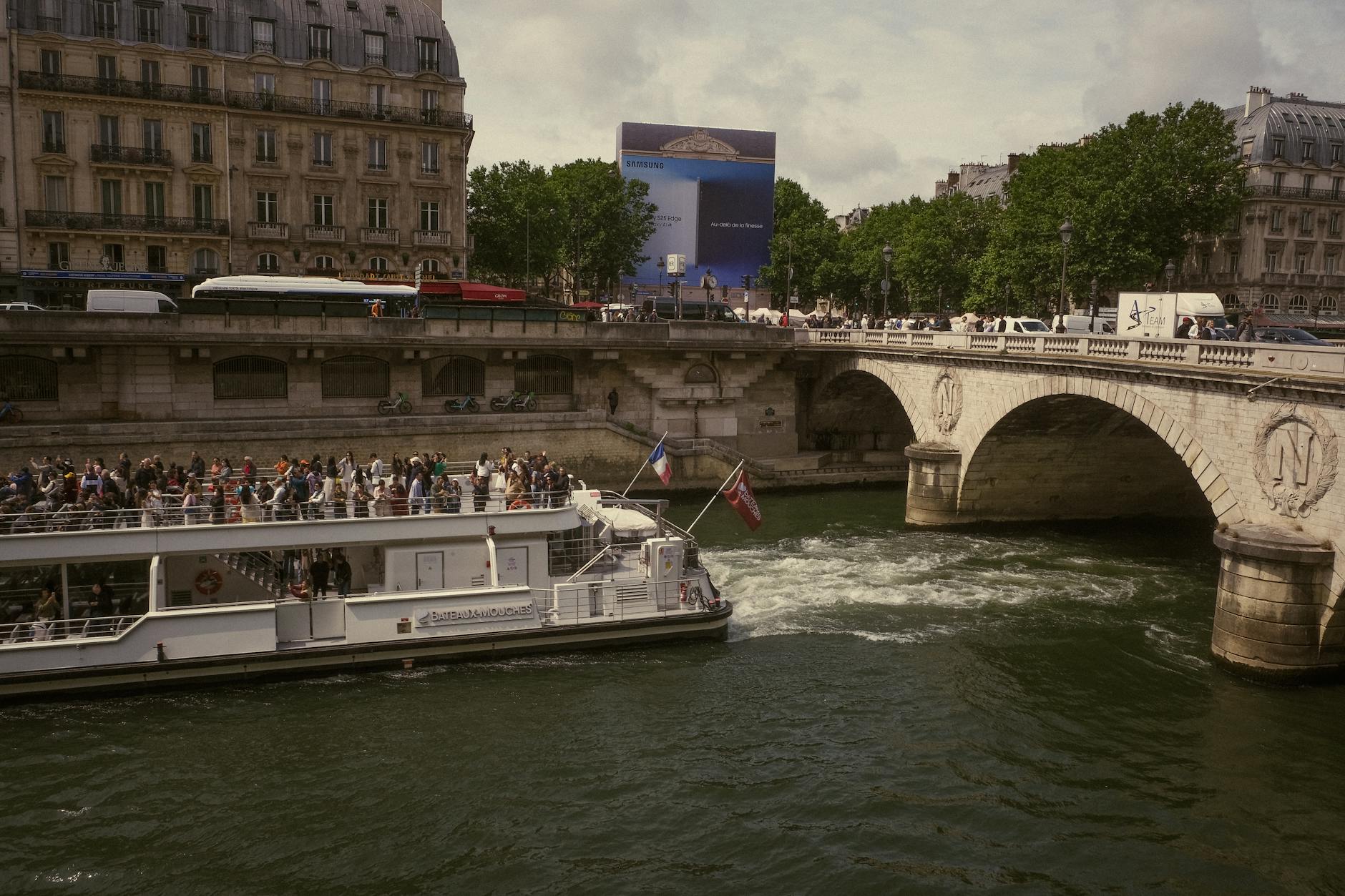 Seine cruise boat passing under a historic Parisian bridge