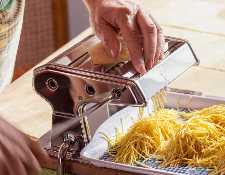 Senior adult making fresh pasta with pasta maker