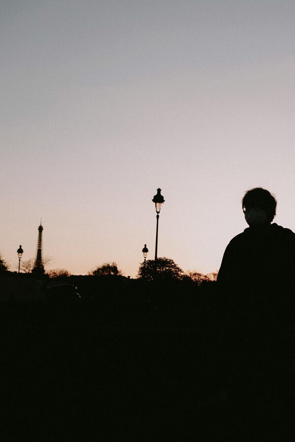 Silhouette of a person with Parisian street lamps and the Eiffel Tower at twilight