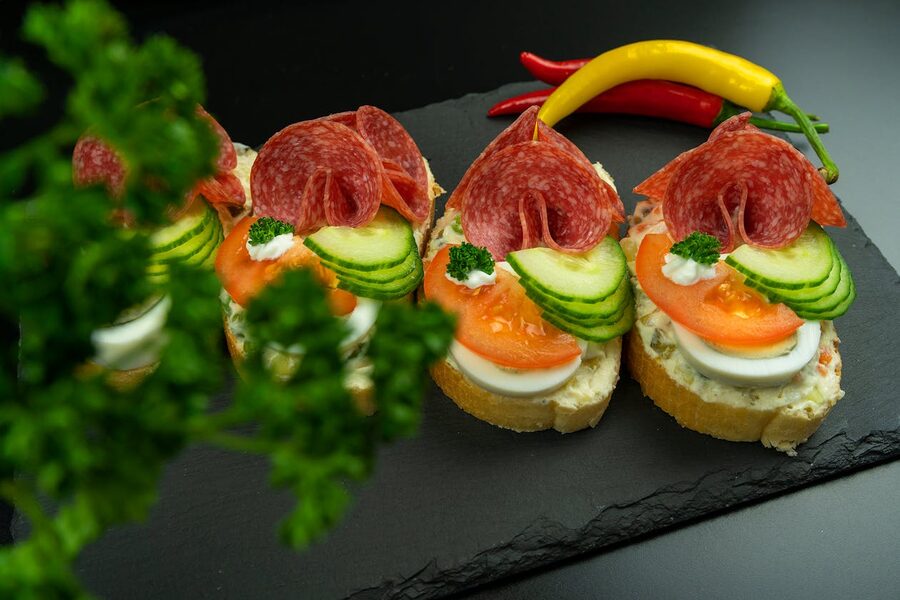 Tasty open-faced smørrebrød sandwiches garnished with fresh vegetables and salami slices