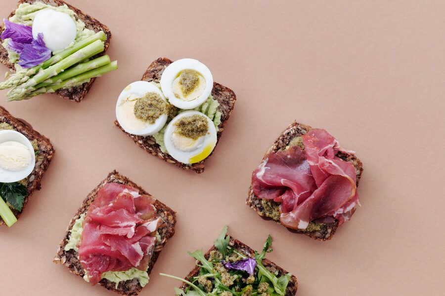 Delicious open-faced smørrebrød sandwiches with gourmet toppings including eggs ham and fresh vegetables