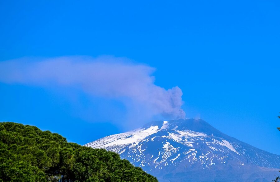 Snow-covered active volcano under blue sky