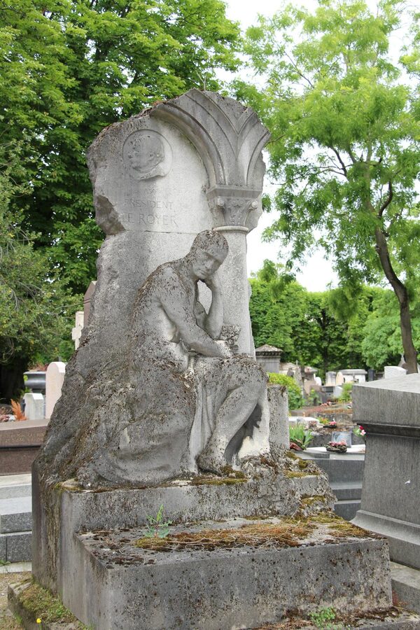 Elegant stone sculpture in Pere Lachaise Cemetery surrounded by lush greenery