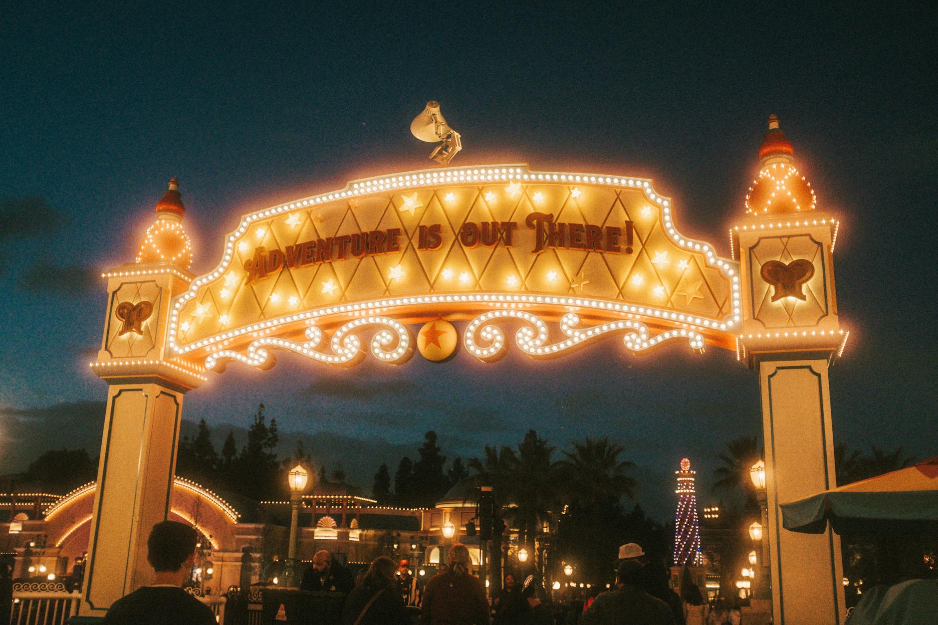 Theme park entrance sign lit up at night