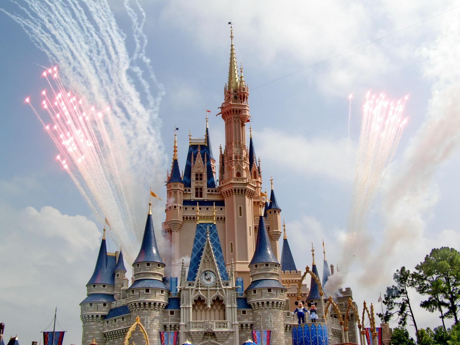 Princess castle illuminated by fireworks and colorful lights at a theme park