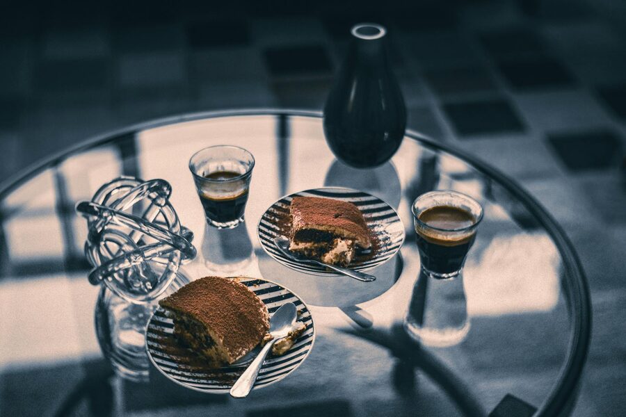 Tiramisu slices and espresso cups on a glass table