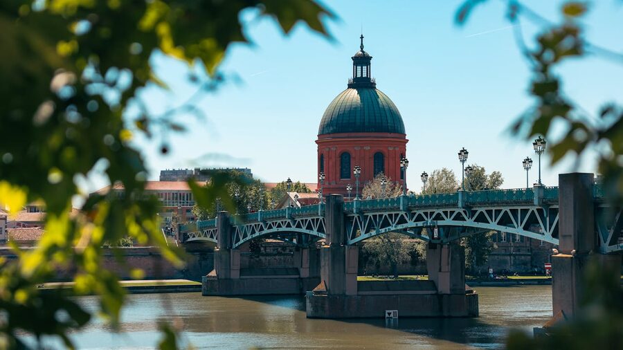 Pont Saint-Pierre and red dome in Toulouse framed by leaves