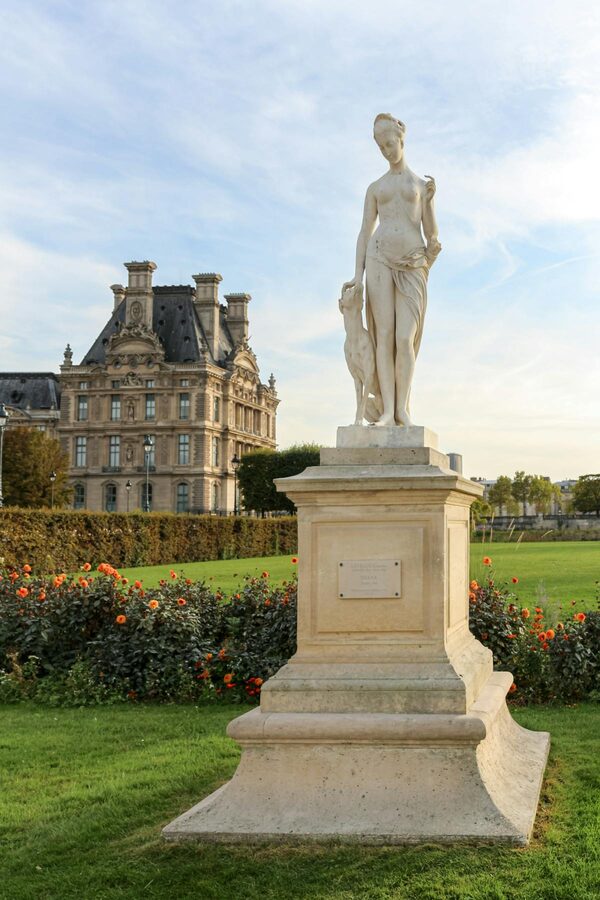 Marble statue in Tuileries Garden with Louvre building in the background