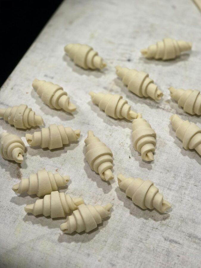 Unbaked croissants laid out on a floured surface ready for baking