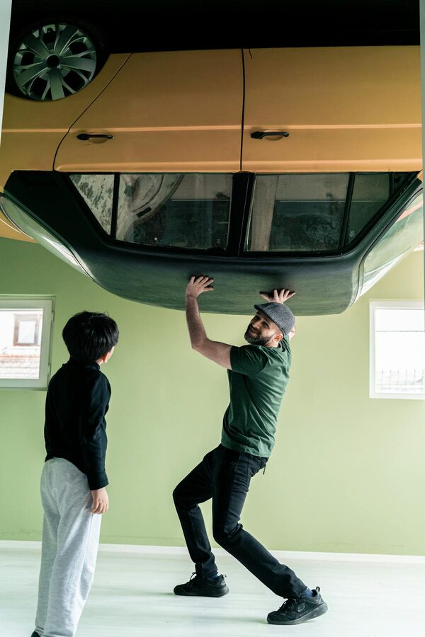 Man and child with an upside-down car display creating an optical illusion