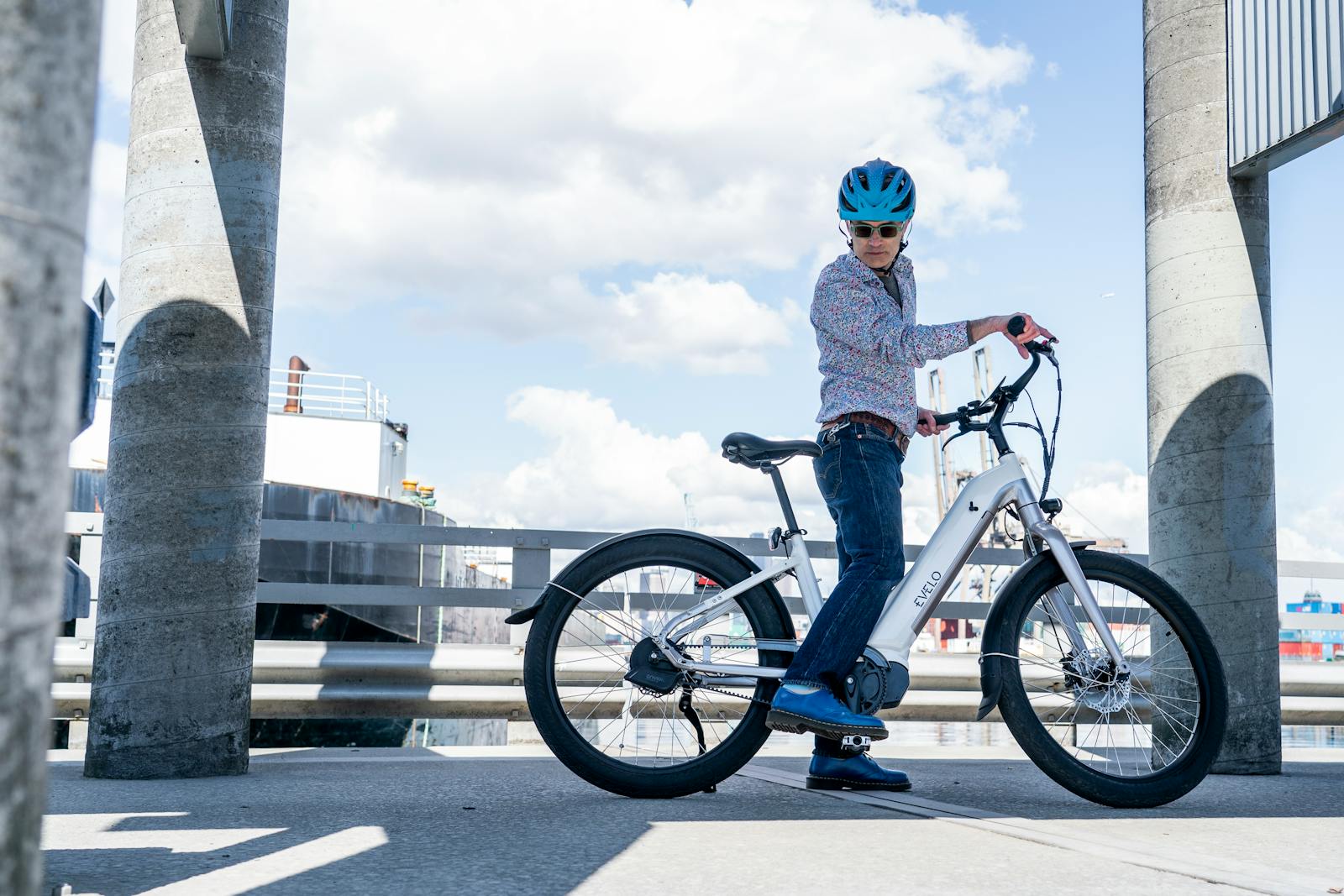 A cyclist riding an electric bike in an urban setting under a blue sky
