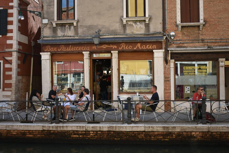 Outdoor dining at a Venetian cafe by a canal