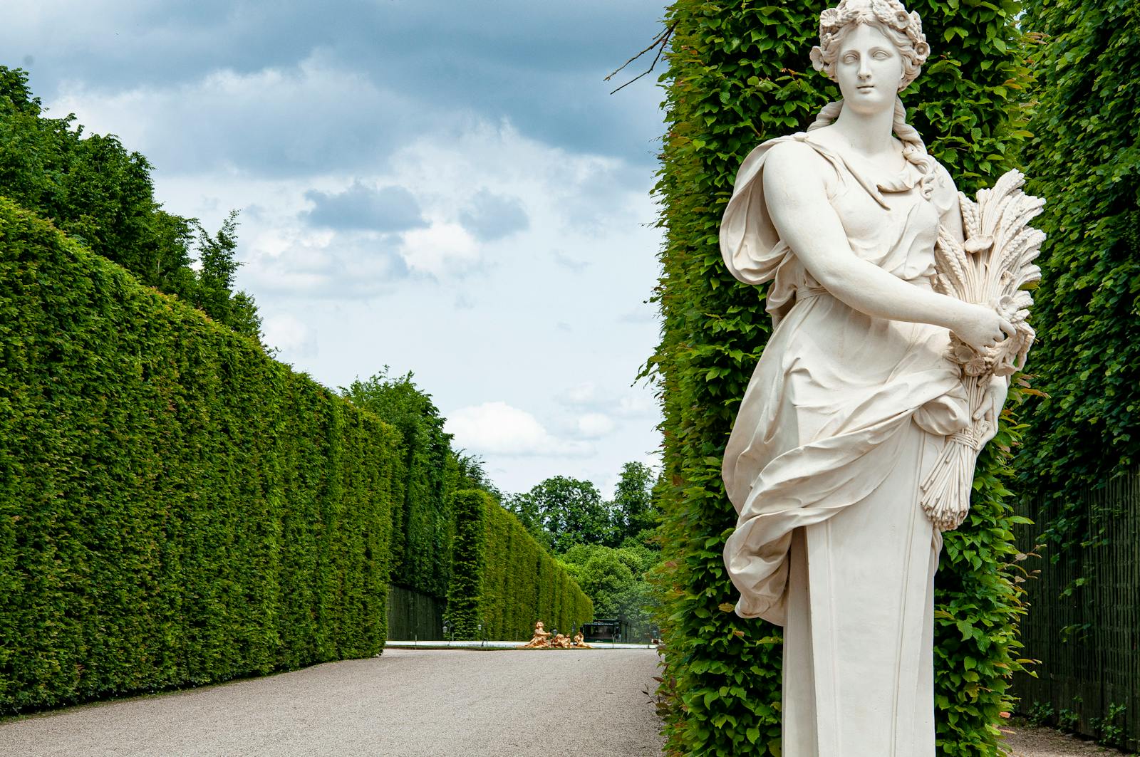 Beautiful marble sculpture amidst hedges in Versailles garden