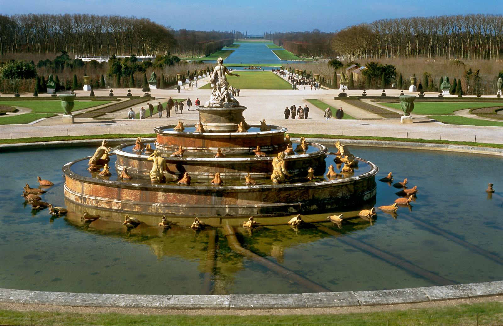 Classic fountain in the Gardens of Versailles surrounded by greenery