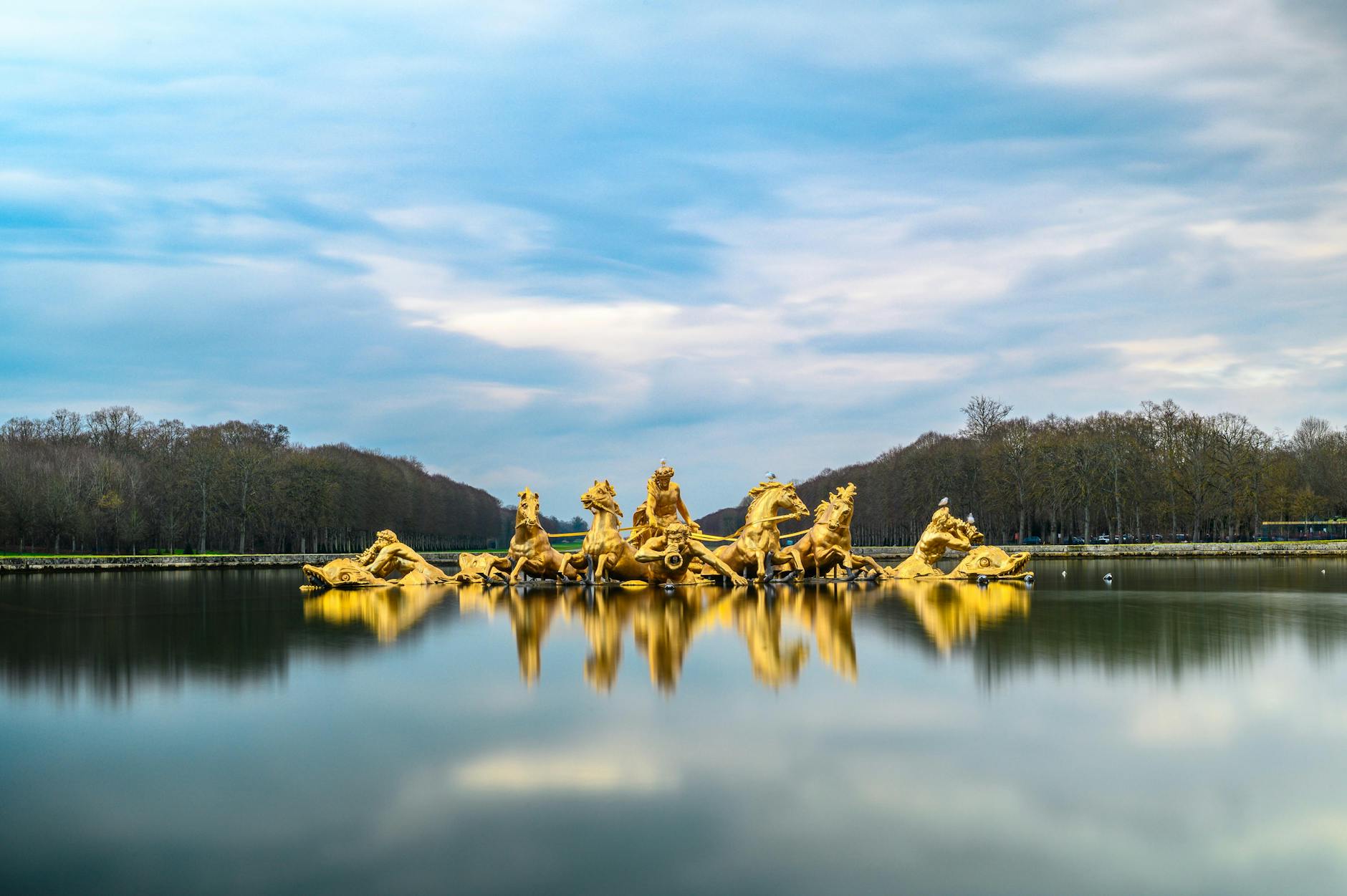 Golden statues in a serene lake at Versailles