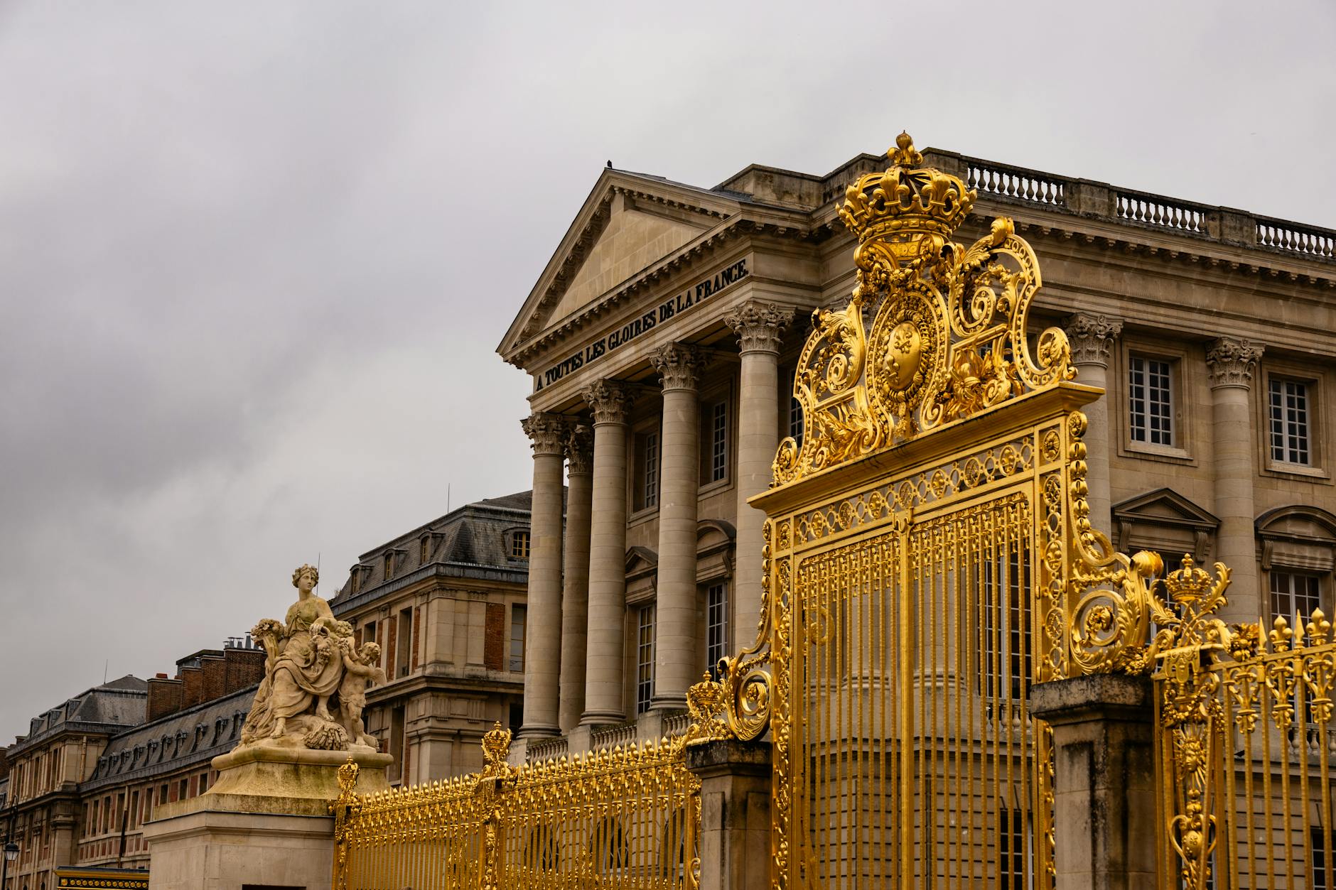 The ornate golden gates at the historical Palace of Versailles