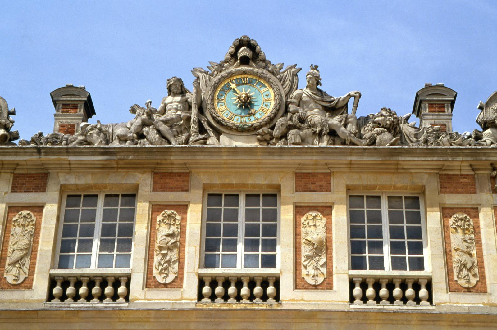 Close-up of ornate clock and sculptures on the facade of the Palace of Versailles