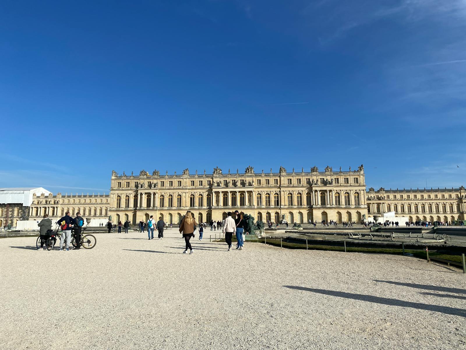 Visitors exploring the historic Palace of Versailles on a sunny day