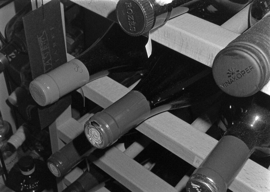 Wine bottles stored on a wooden rack in monochrome