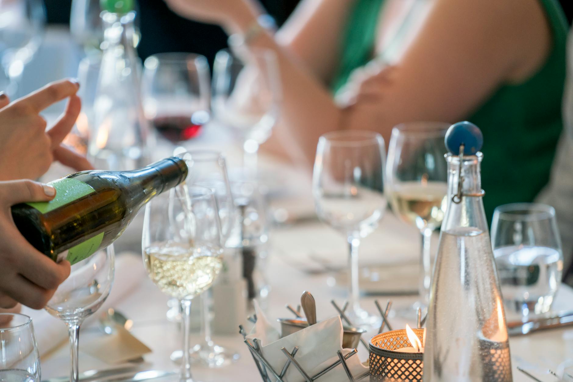Wine being poured into a glass at a fine dining table setting