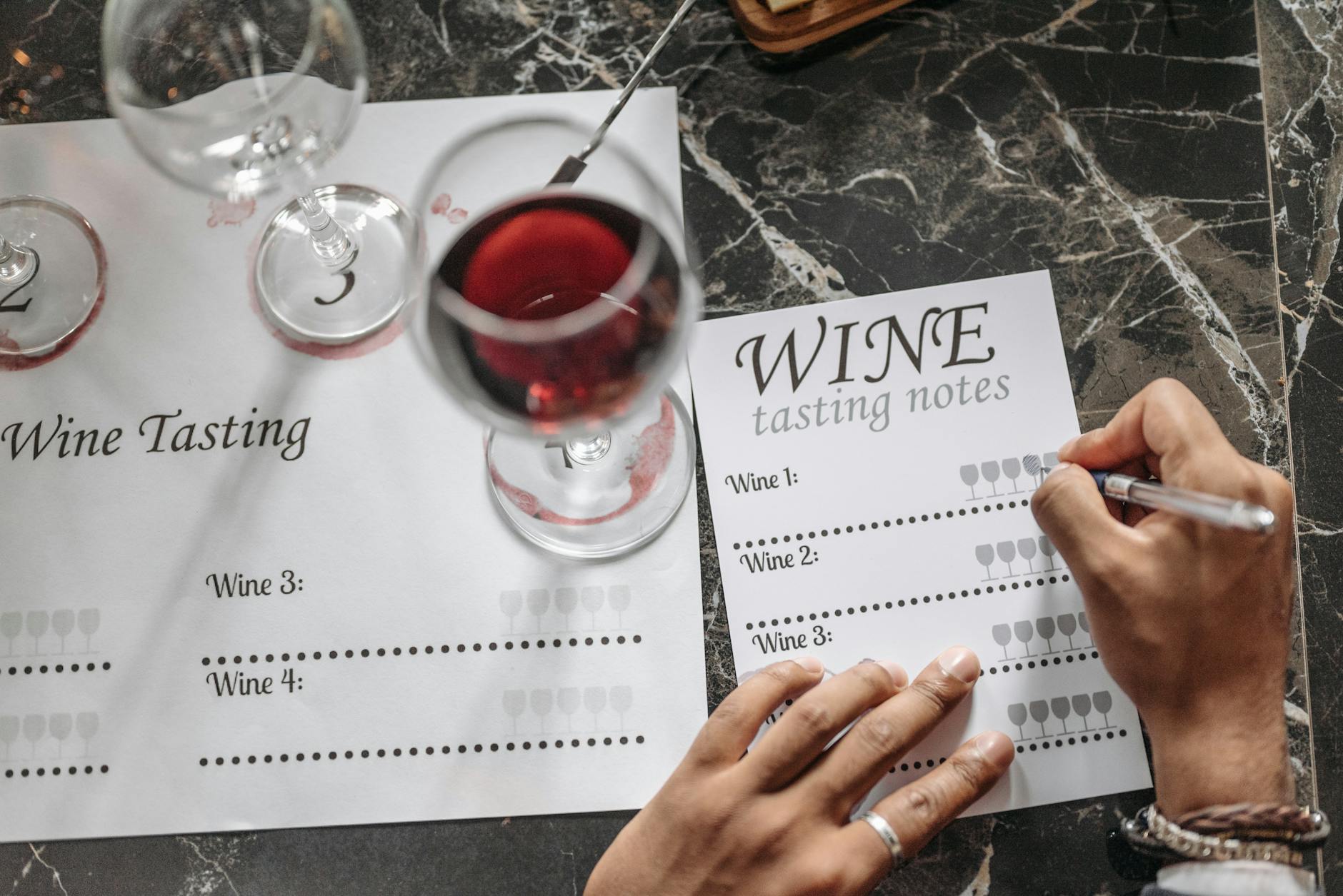 Wine tasting session with notes and glasses on a marble surface