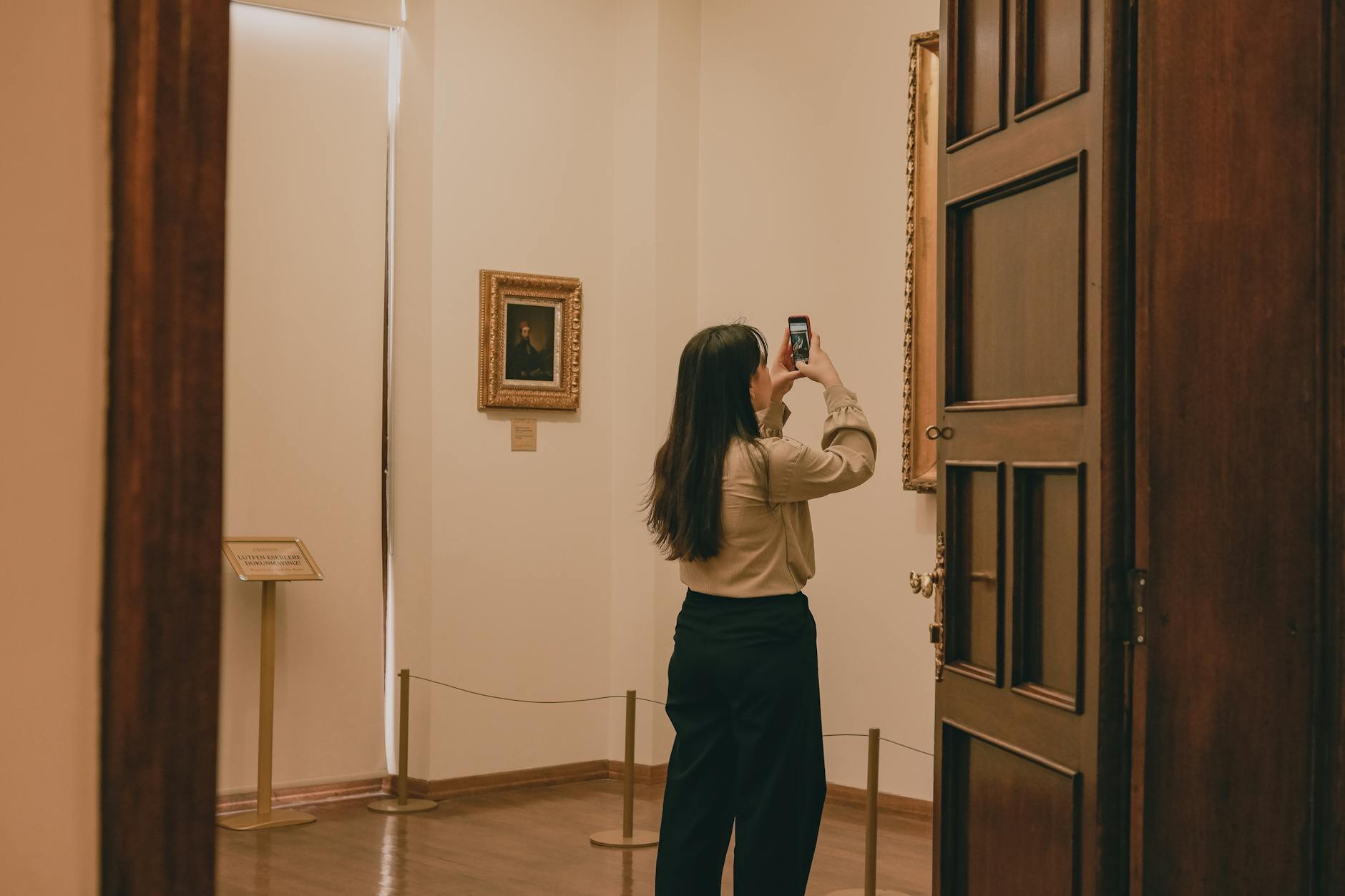 A woman capturing artwork with a phone in a tranquil museum setting