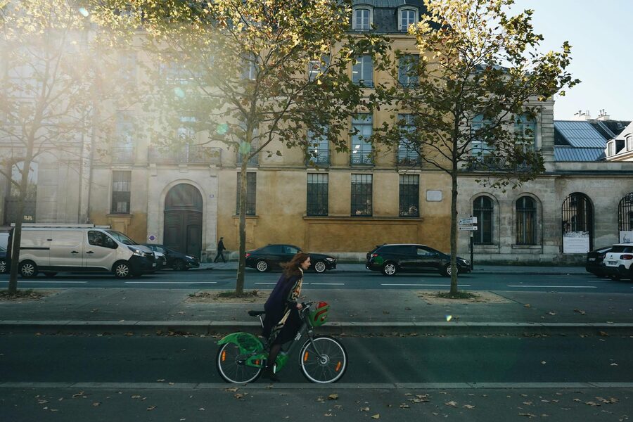 Woman cycling through a city street on an autumn day