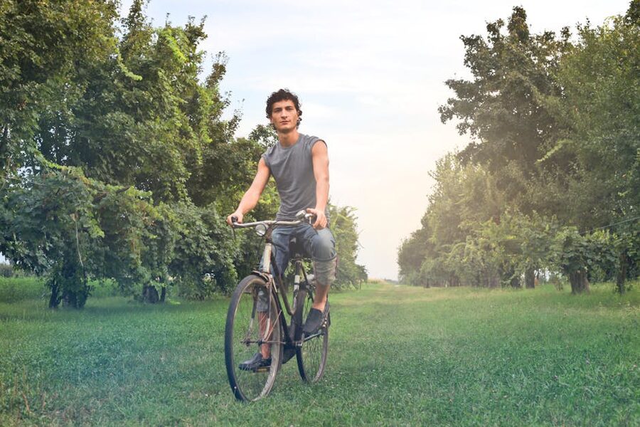Young man on bike ride green scenery