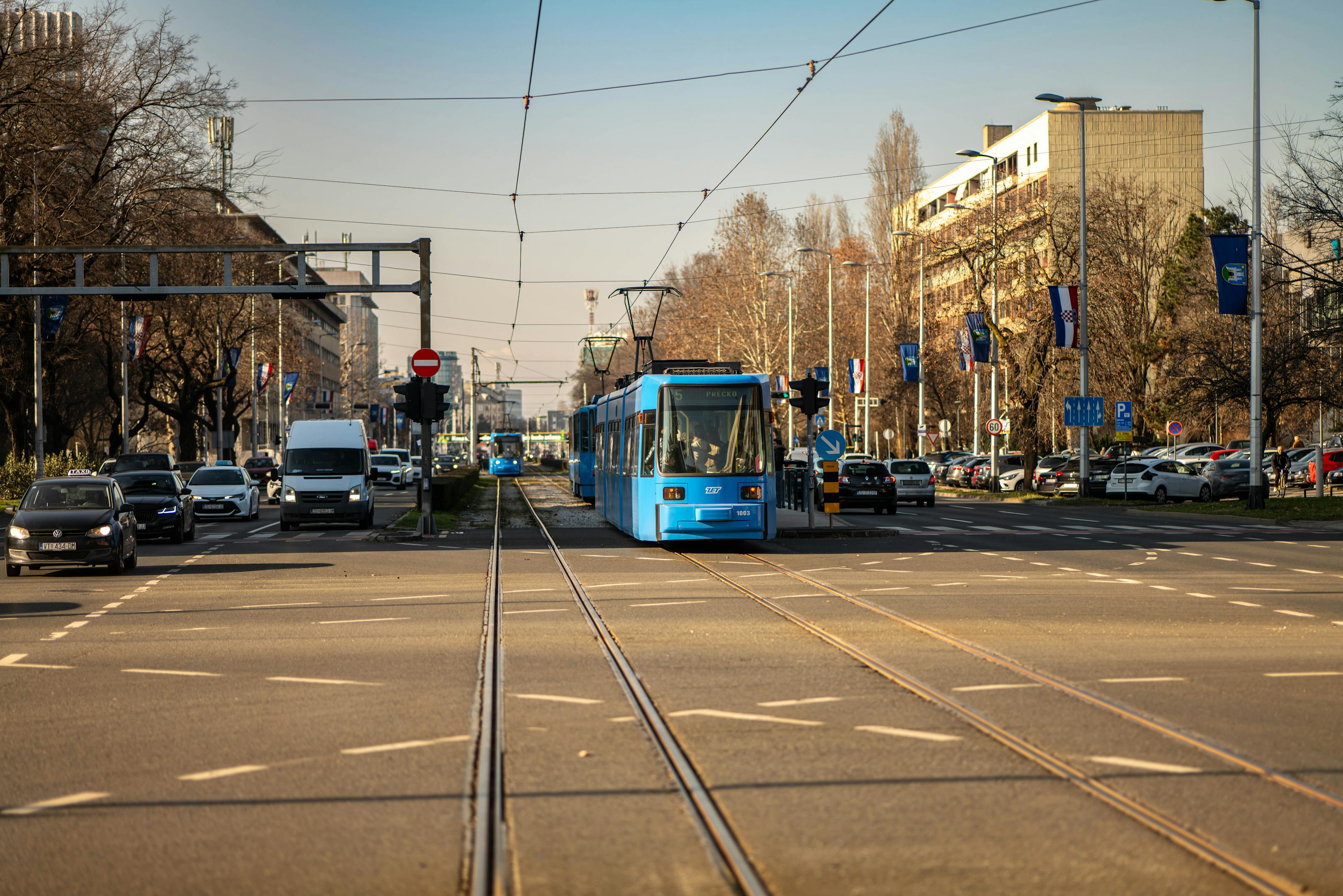Blue tram traversing a busy street in Zagreb, Croatia's urban landscape