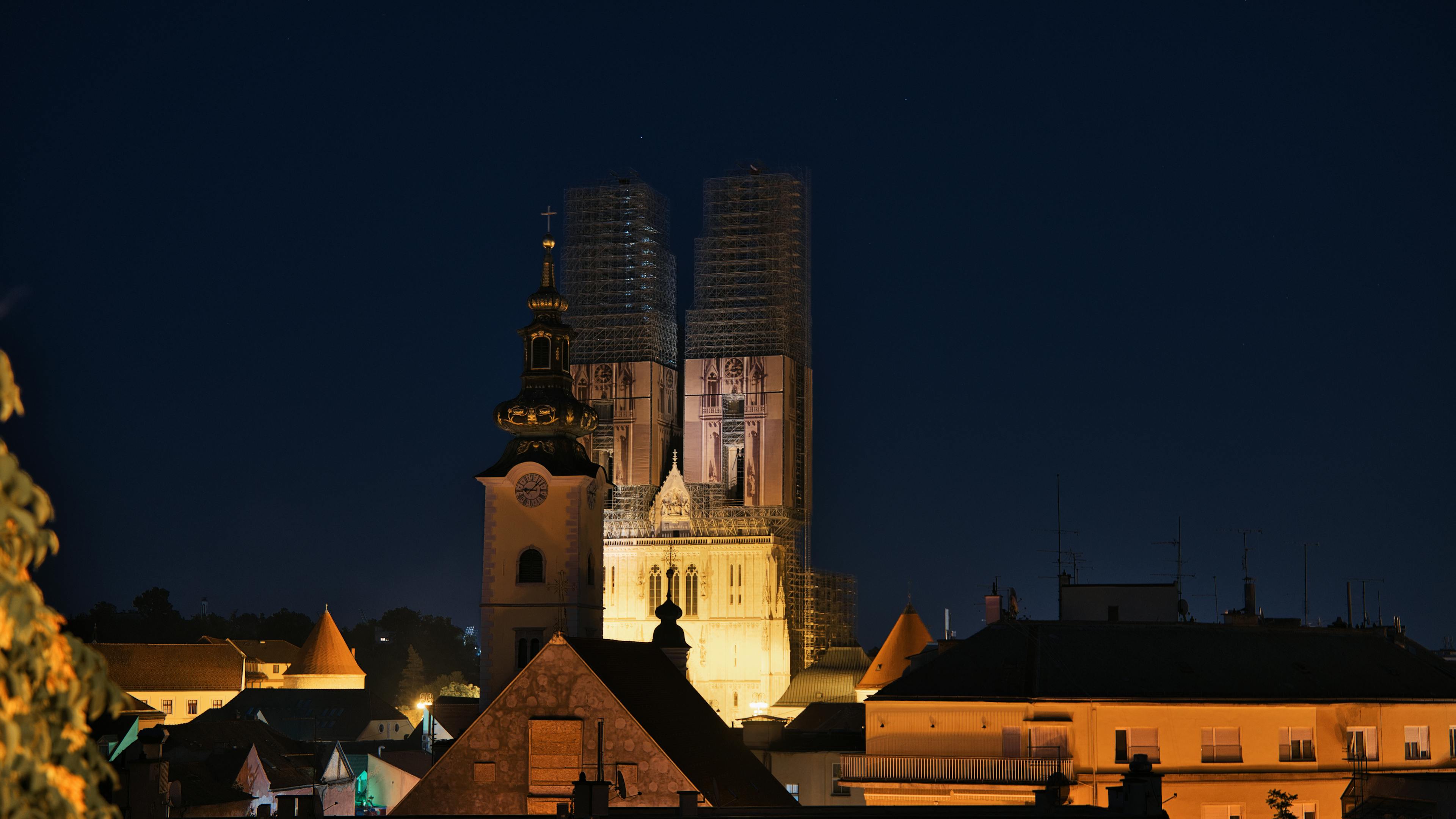 Night view of the illuminated Zagreb Cathedral, surrounded by rooftops