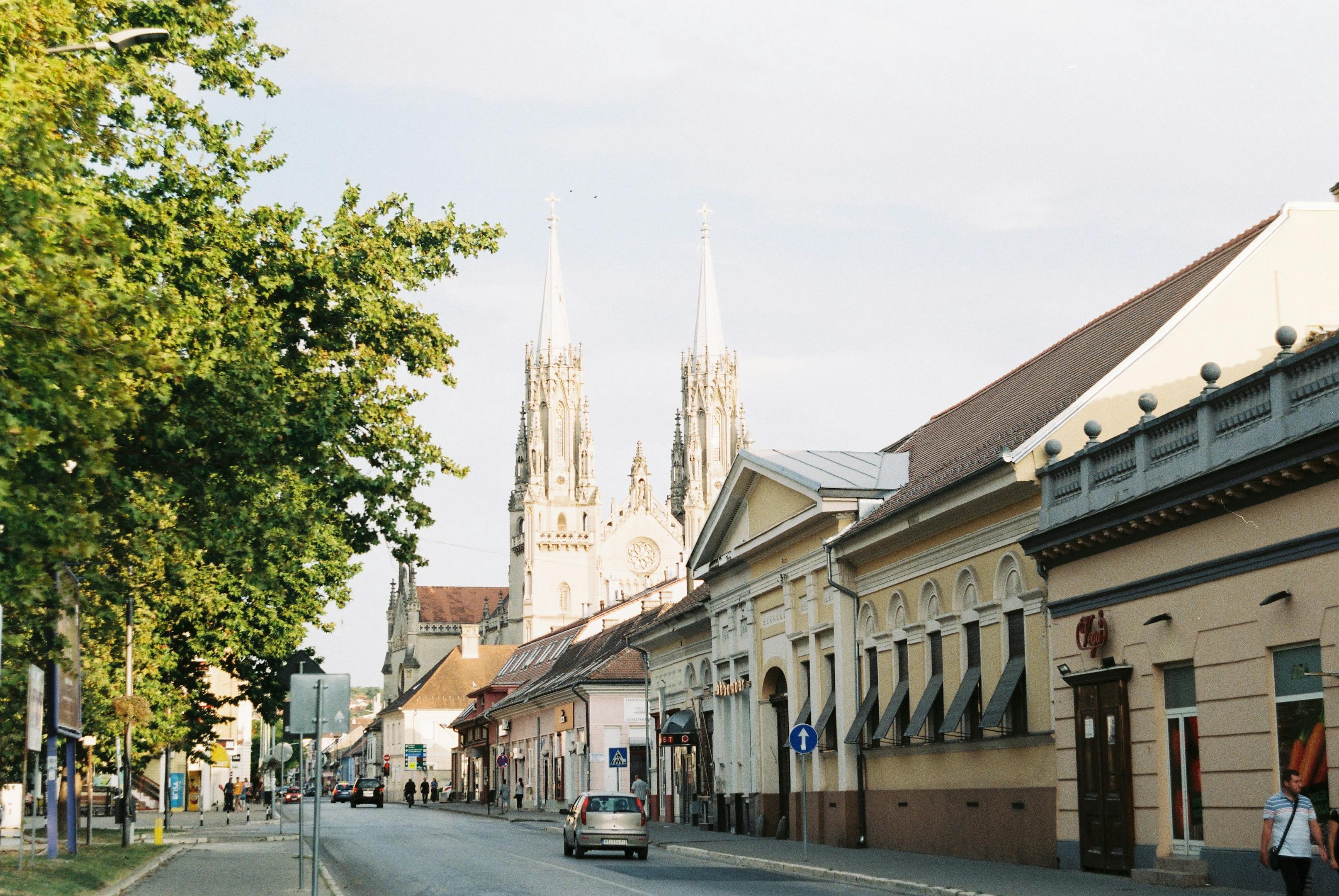 A picturesque European street with a historic cathedral in the background, bathed in sunlight