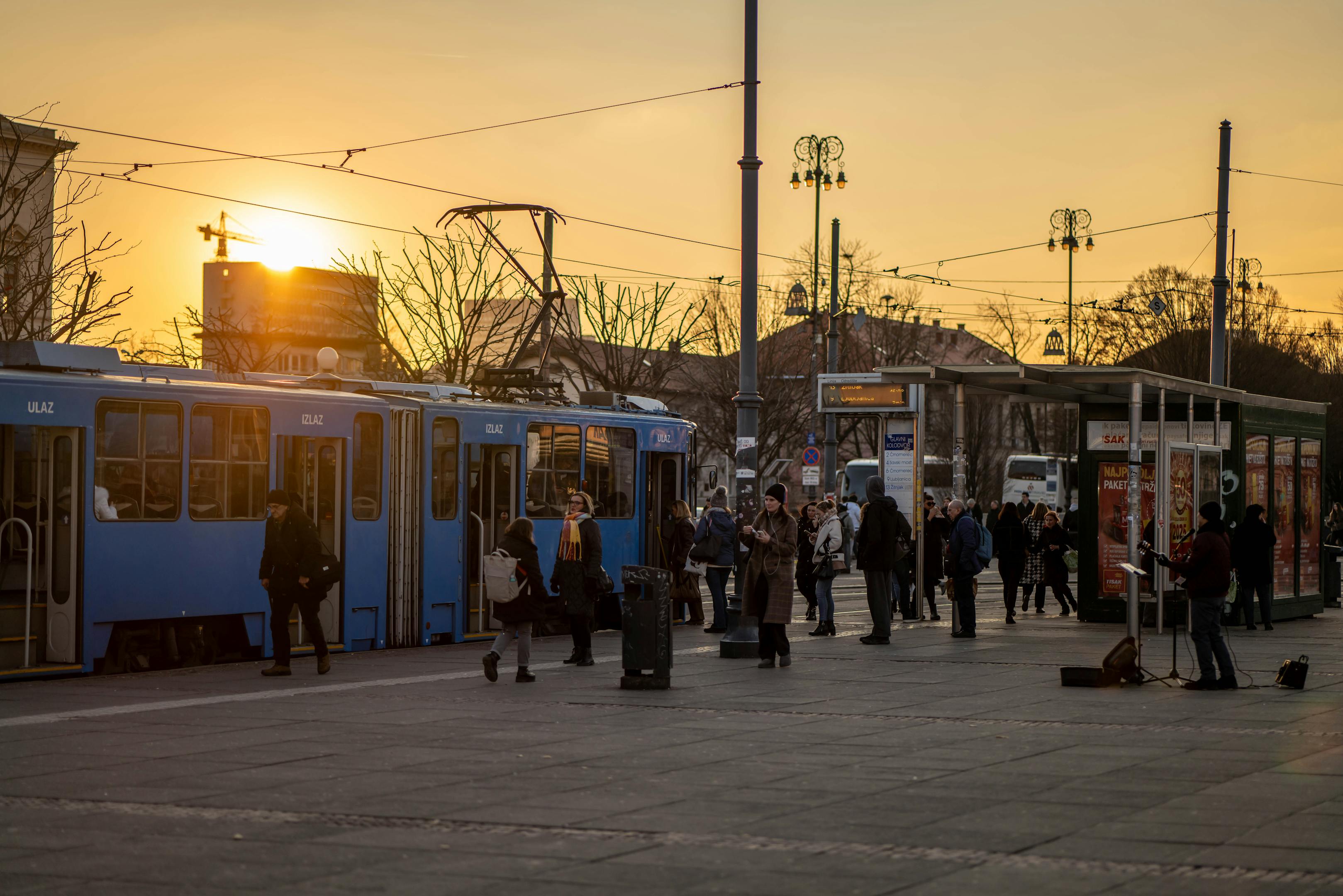People boarding trams during sunset in Zagreb, creating a vibrant urban scene with warm tones